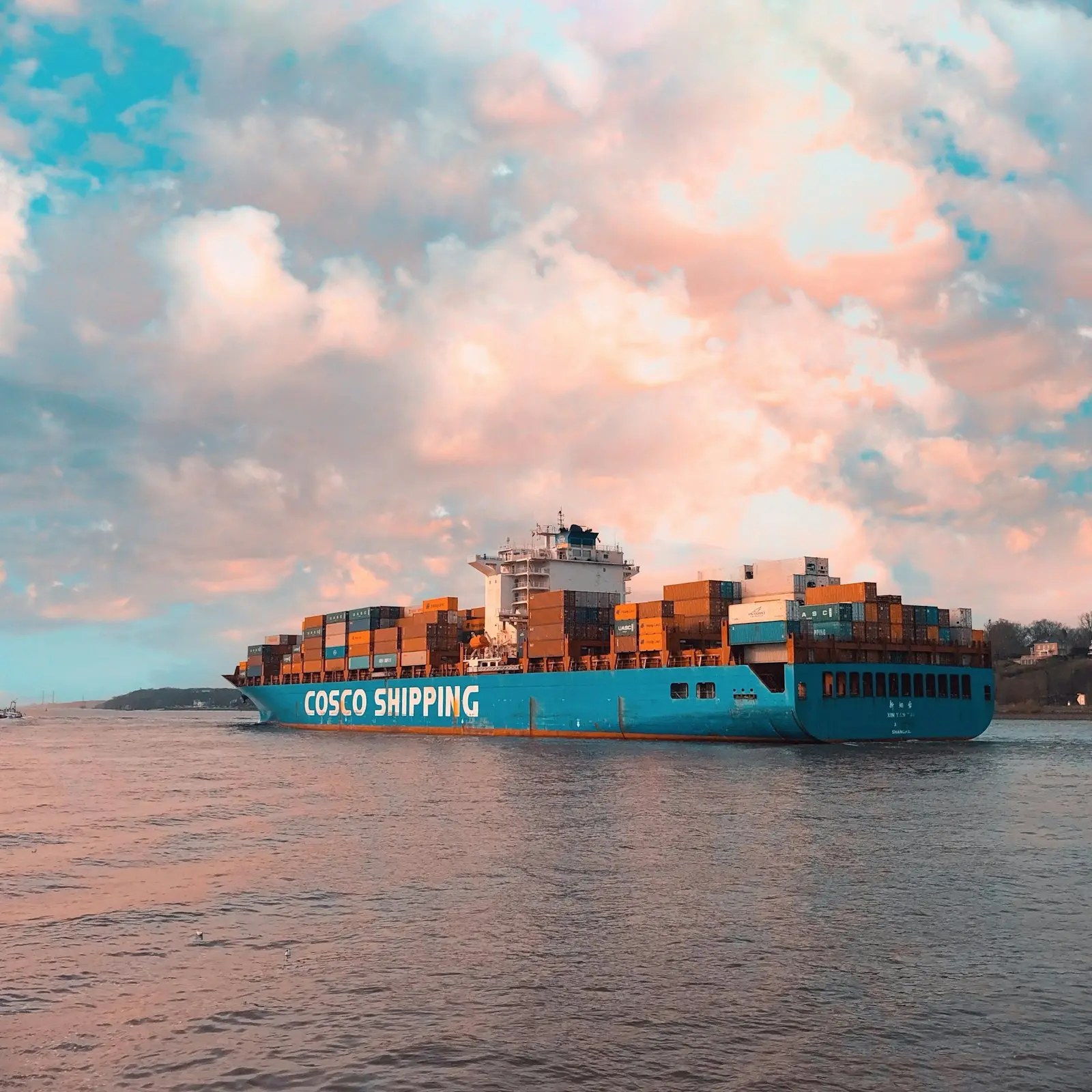 Loaded container vessel at sea under a pink sky