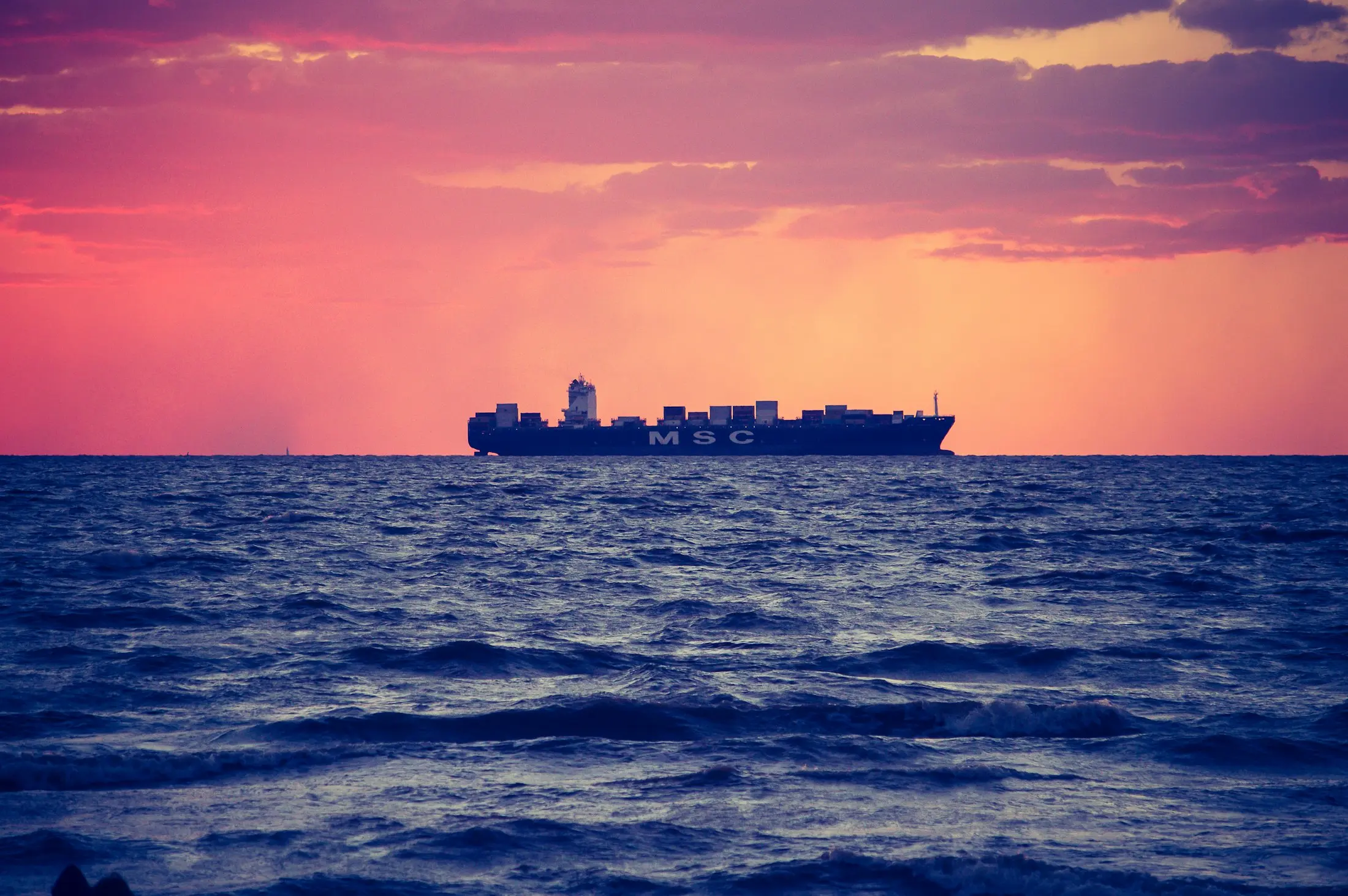 Container ship crossing open sea at dusk