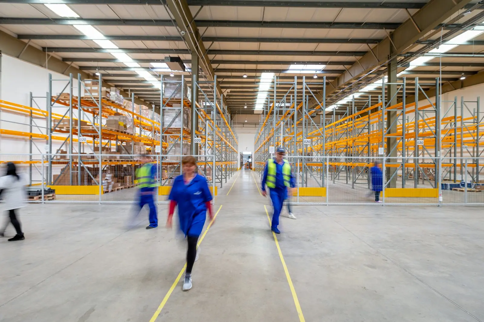 Warehouse staff walking along racked storage aisles