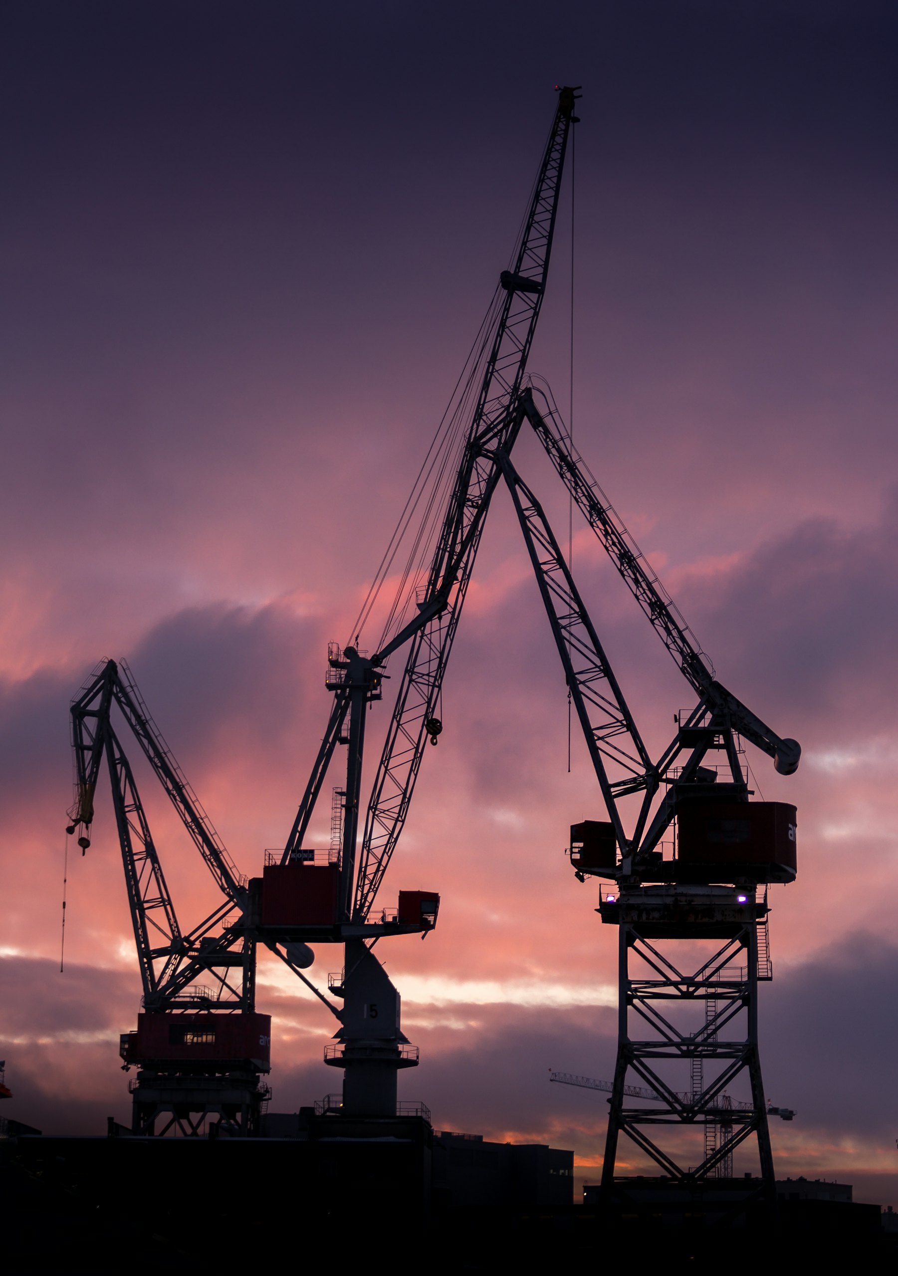 Port cranes silhouetted against a dusk sky