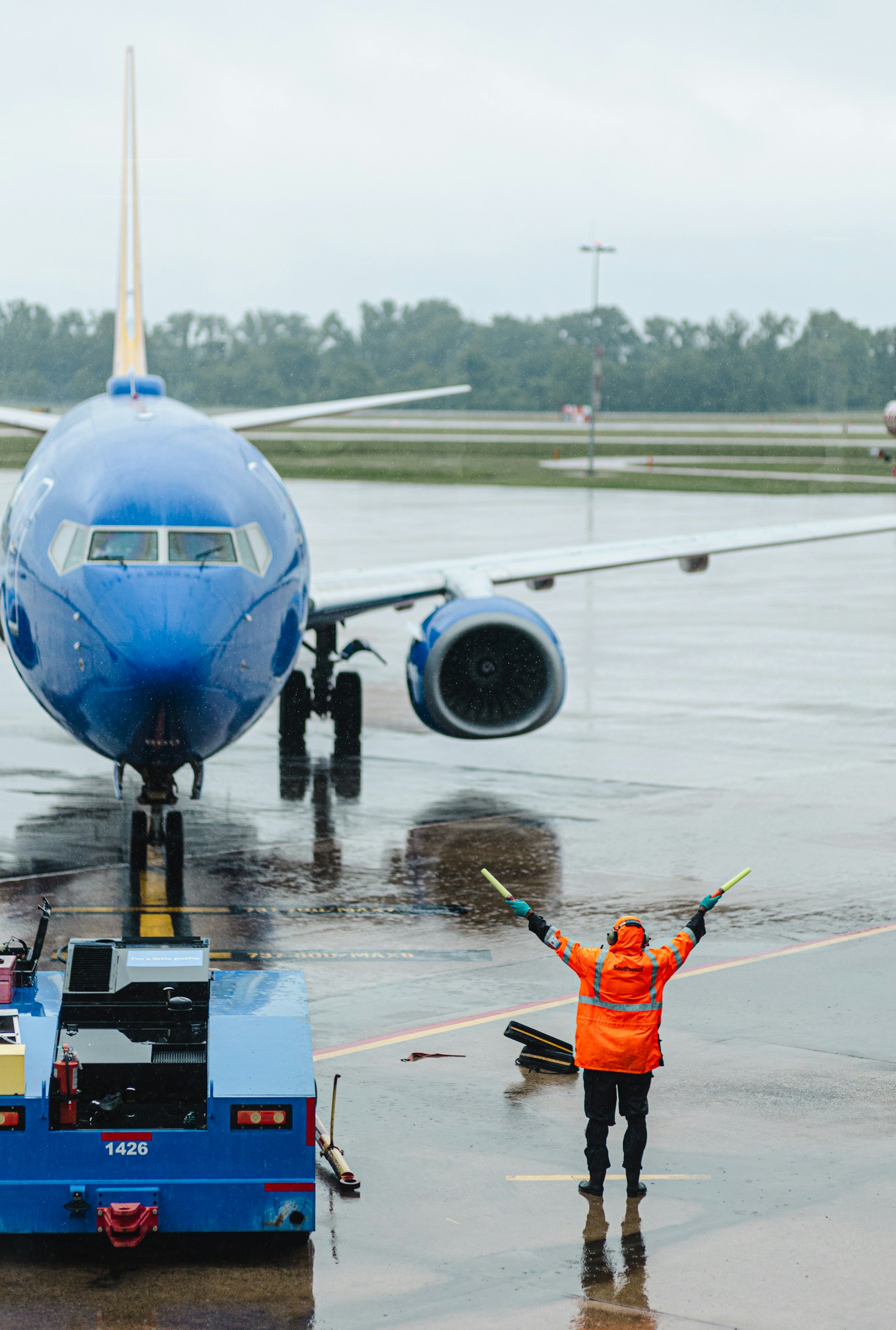 Marshaller guiding an aircraft on a wet apron