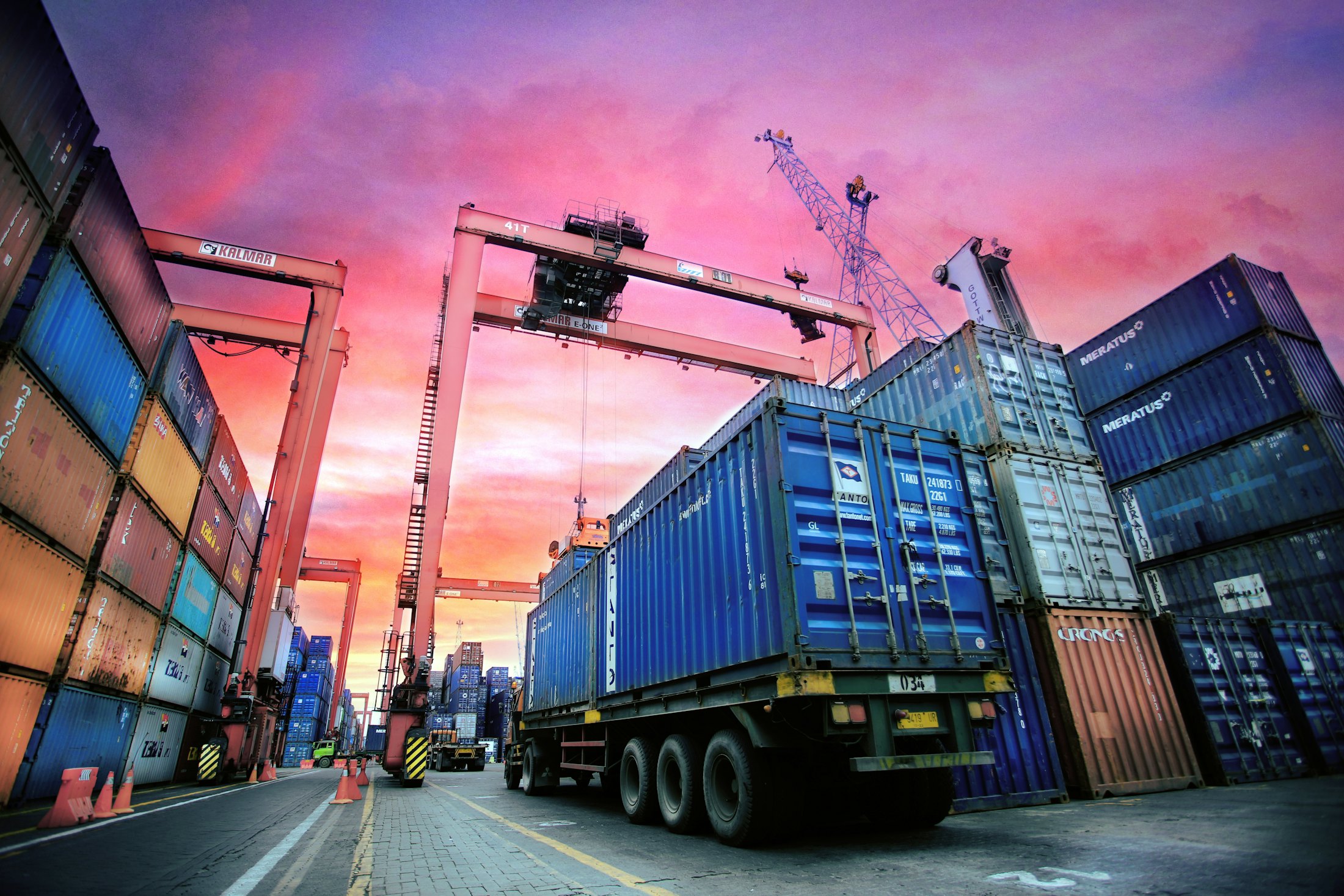 Container terminal cranes and trucks at sunset