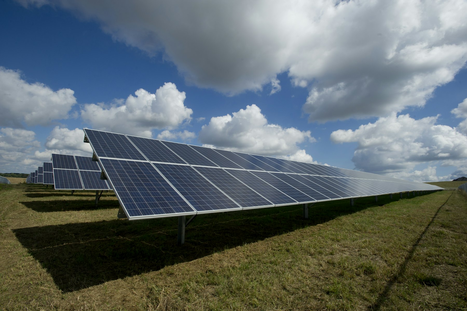 Solar panels in a grassy field under a cloudy sky